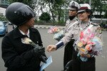 Seorang polisi wanita memberi setangkai bunga mawar kepada seorang pengendara motor untuk menandai Hari Valentine di Jakarta, 14 Februari 2012. Hari itu dianggap haram atau terlarang di propinsi Aceh, Indonesia. [Reuters]