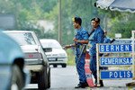 Polisi Malaysia menjaga sebuah pos pemeriksaan dekat perbatasan Malaysia-Thailand di desa Jeram Perdah, sekitar 550 km di timur laut Kuala Lumpur. Para penyelundup manusia mencoba menyelinapkan para pendatang ilegal yang bersembunyi di truk atau bagasi mobil ke dalam negara-negara itu. [Bazuki Muhammad/Reuters]